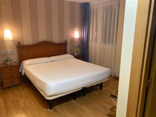 a bedroom with a white bed and a wooden floor at Hotel Villa De Ermua in Ermua