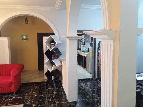 a living room with a red couch and an archway at MiniGolf, MeteoMode & B2B RESIDENCE Ekoumdoum - DAHARA APPARTS in Yaoundé