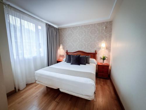 a bedroom with a large white bed and a window at Hotel Villa De Ermua in Ermua