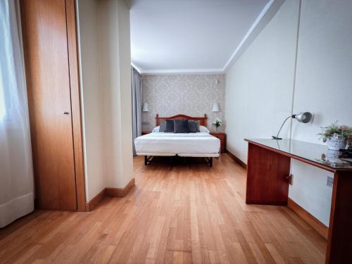 a bedroom with a white bed and a wooden floor at Hotel Villa De Ermua in Ermua