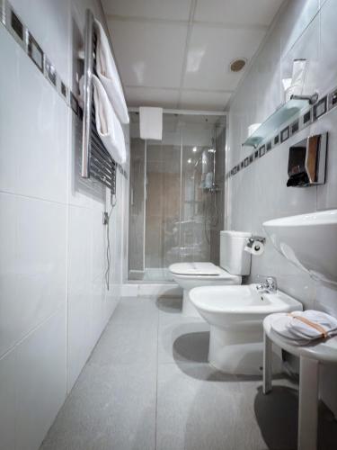 a white bathroom with two toilets and a sink at Hotel Villa De Ermua in Ermua