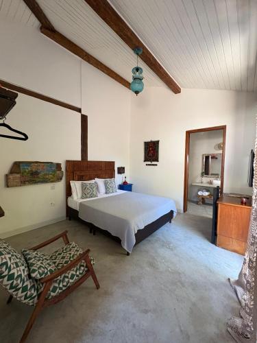 a bedroom with a large bed and a chair at Gizele Sander Arte & Hospedagem in Ilhabela