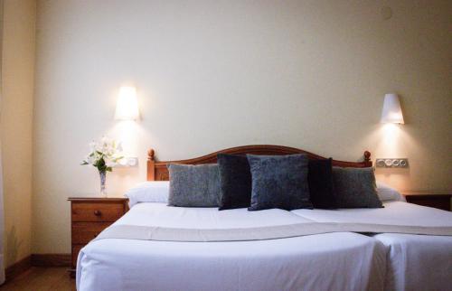 a bedroom with two beds with white sheets and blue pillows at Hotel Villa De Ermua in Ermua