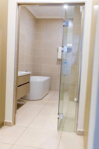 a bathroom with a tub and a glass shower door at Emarald sky views in Johannesburg