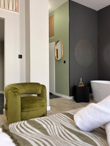 a bedroom with a green chair and a tub at TINTURA by BAST - Wanna, Antresola, OFF Piotrkowska, EC1 ,Stajnia Jednorożca, Winda, Parking na Terenie, Orientarium, Hopa Lupa, ATLAS ARENA in Łódź