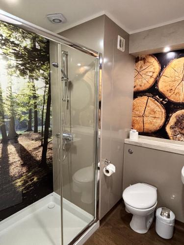 a bathroom with a shower and a toilet and trees at Fox Lodge with Hot Tub in Cupar