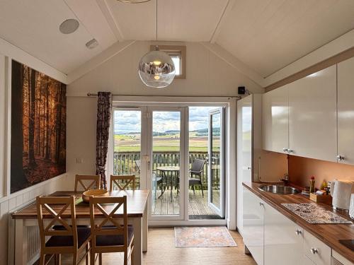 a kitchen with a table and a dining room at Fox Lodge with Hot Tub in Cupar