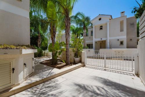 a house with a white fence and palm trees at Anthorina Gardens Retreat in Aglantzia
