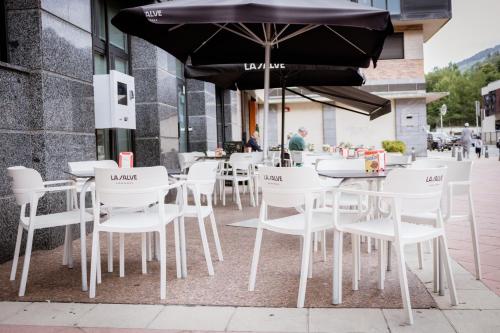 a group of white tables and chairs with an umbrella at Hotel Villa De Ermua in Ermua
