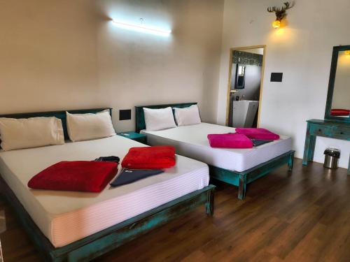 two beds in a room with red pillows on them at Gambhiraa Resorts in Kolli Hills