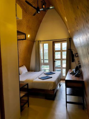 a bedroom with a bed and a desk in a room at Gambhiraa Resorts in Kolli Hills
