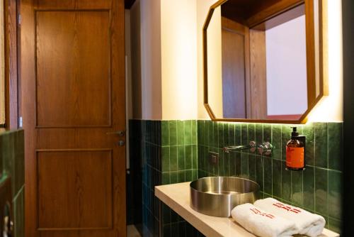 a green tiled bathroom with a sink and a mirror at Villa Saf in Bharsaf