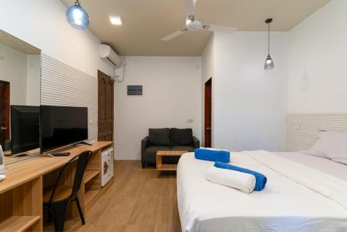 a bedroom with a bed and a desk with a television at Villa Crescenta in Ukulhas