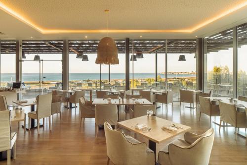 Un restaurante con mesas y sillas y vista al mar. en Palmares Beach House Hotel - Adults Friendly, en Lagos