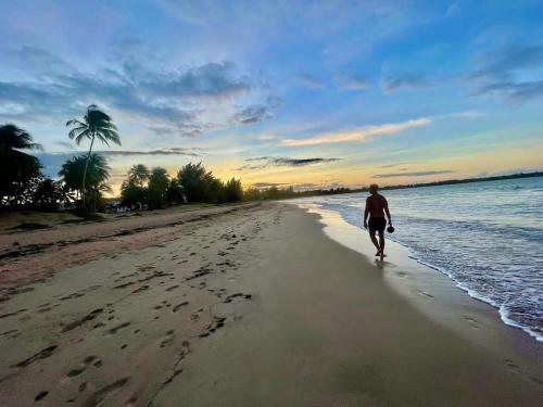 a man walking on the beach at sunset at Casa Encantosyour ideal beachfront destination in Las Coles