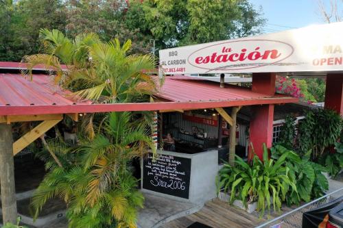 a restaurant with a sign and palm trees in front of it at Casa Encantosyour ideal beachfront destination in Las Coles