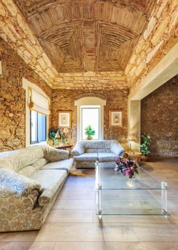 a living room with a couch and a stone wall at Spacious house with sea view in Quelfes, shared pool in Quelfes