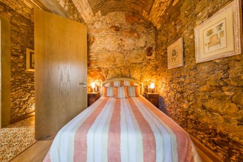 a bed in a room with a stone wall at Spacious house with sea view in Quelfes, shared pool in Quelfes