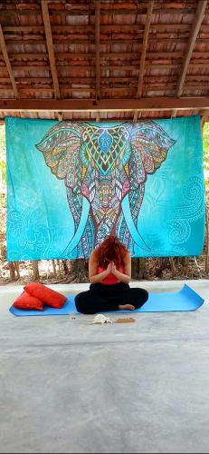 une femme assise par terre devant une peinture murale dans l'établissement Ginger Harmony Guesthouse and Cafe, à Tangalle