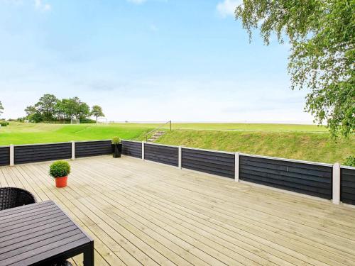 a wooden deck with a view of a golf course at Seaside Bliss with Spa - By Traum Ferienwohnungen in Otterup