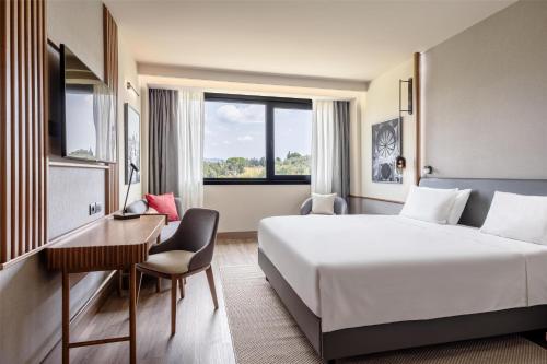 a hotel room with a bed and a desk and a window at Radisson Blu Hotel, Florence in Florence