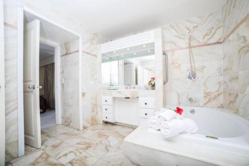 a white bathroom with a tub and a sink at Charming apartment in Lowlands with shared pool, 87 m² in Lowlands