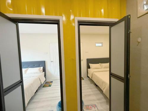 a bedroom with two beds and a yellow wall at 69 Comfortainer Homestay in Taiping