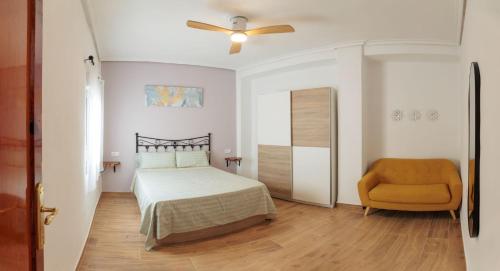 a bedroom with a bed and a ceiling fan and a chair at Apartamento Estilo Rustico Buñol - ELPATIO- in Buñol