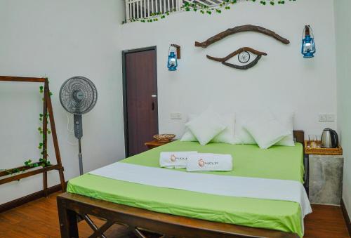a bedroom with a green bed with two towels on it at Ramya Ru Nature Resort in Galle