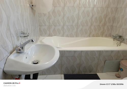 a bathroom with a sink and a bath tub at Raneziah Guesthouse in Kasane