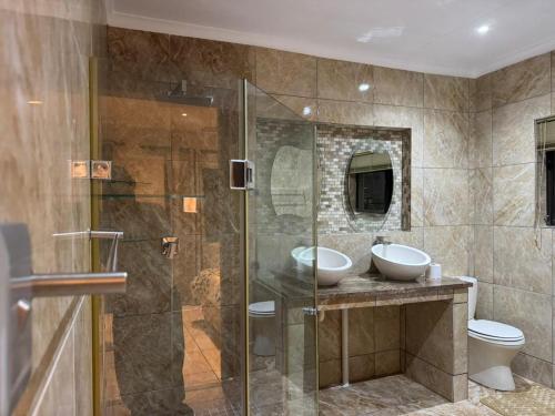 a bathroom with two sinks and a glass shower at Manganese Luxury Stay in Nelspruit