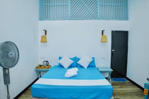 a bedroom with a blue bed and a fan at Ramya Ru Nature Resort in Galle