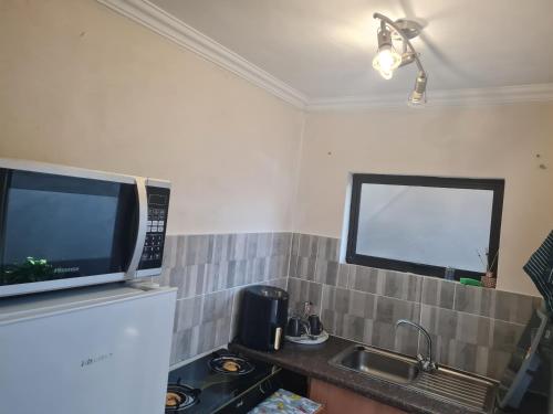 a kitchen with a sink and a tv on the wall at Cheryl's Fortress in Johannesburg