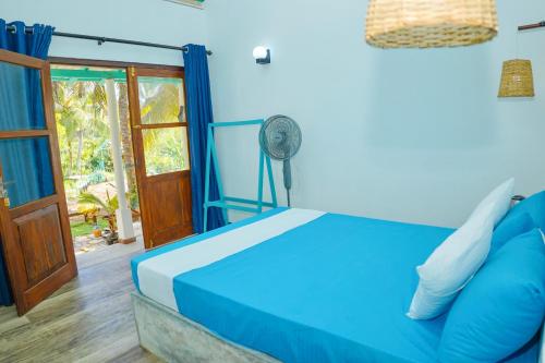 a bedroom with a blue bed and a fan at Ramya Ru Nature Resort in Galle