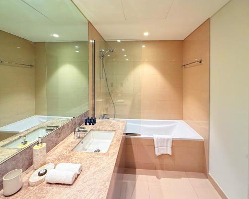 ein Badezimmer mit Badewanne, Waschbecken und Dusche in der Unterkunft Iconic Burj Khalifa, Fountain Views, Luxury 2BR in Sabkhah