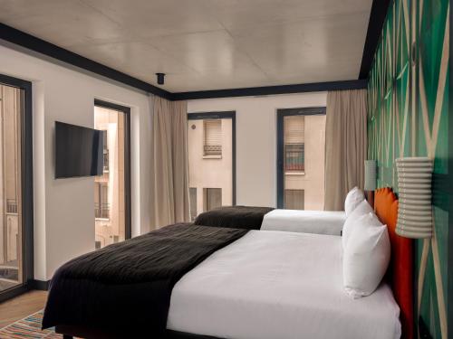 a bedroom with a large white bed and a flat screen tv at Chachacha Hôtel in Nantes