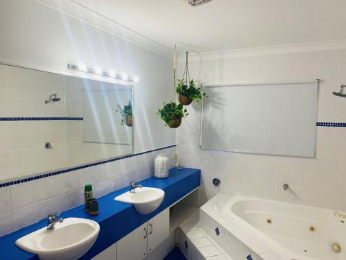 a bathroom with two sinks and a tub and a mirror at Sandys On Cypress - Rainbow Beach, pets welcome in Rainbow Beach