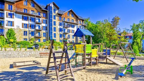 un parco giochi nella sabbia di fronte a un edificio di Resort Karkonosze, Sun & Snow a Szklarska Poręba
