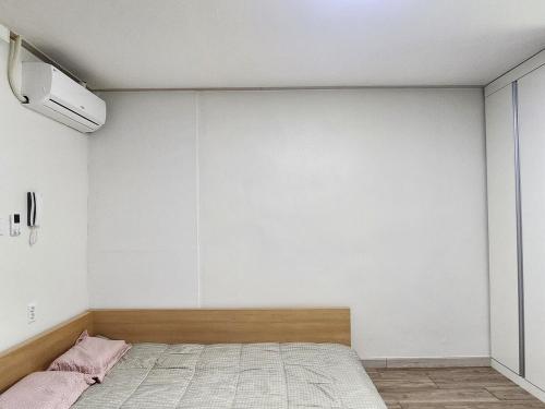 a bedroom with a bed and a white wall at J 9-minute walk from Nakseongdae Station, quiet neighborhood studio in Samgong