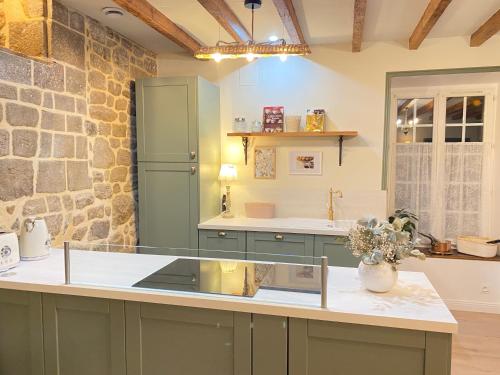 a kitchen with green cabinets and a stone wall at Les gites Romeline in Montviron