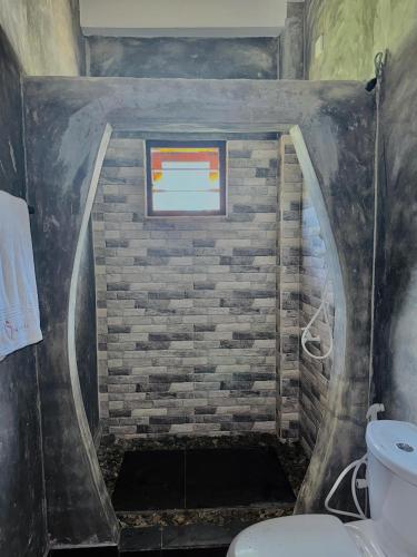 a bathroom with a toilet and a brick wall at Ramya Ru Nature Resort in Galle