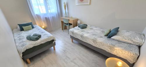 a bedroom with two beds and a desk in it at Le Panorama des Pyrénées in Tarbes