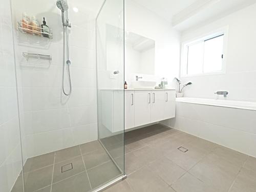 a white bathroom with a shower and a sink at Spacious 4 Bedroom Hunter Home in Bellbird