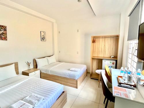 a hotel room with two beds and a desk with a desk at Dreamie Trip and Travel Home in Ho Chi Minh City