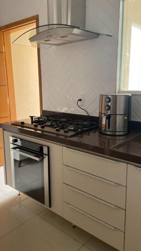 a kitchen with a stove and a microwave at Royal Lion Bedroom in Londrina
