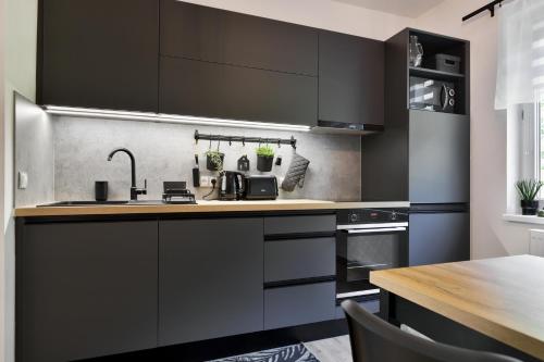 a kitchen with black cabinets and a wooden table at Apartmány Hřensko in Hřensko