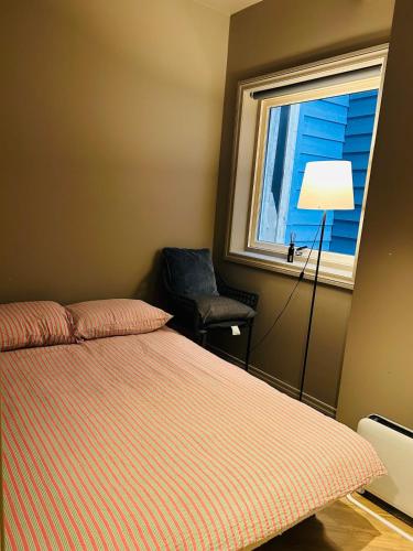 a bedroom with a bed and a window and a chair at Cozy place in the city center, Bergen! in Lii