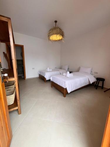 a bedroom with two beds and a chandelier at Riad TAWALA Surfing Mind in Tamraght Ouzdar