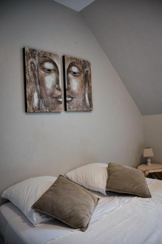 three pictures of two faces on the wall above a bed at Auberge de la fontaine aux loups in Saint-Sulpice-le-Dunois