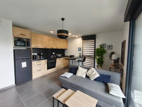 a living room with a blue couch and a kitchen at STELLA Modern apartment, terrace and sea view Donville in Donville-les-Bains